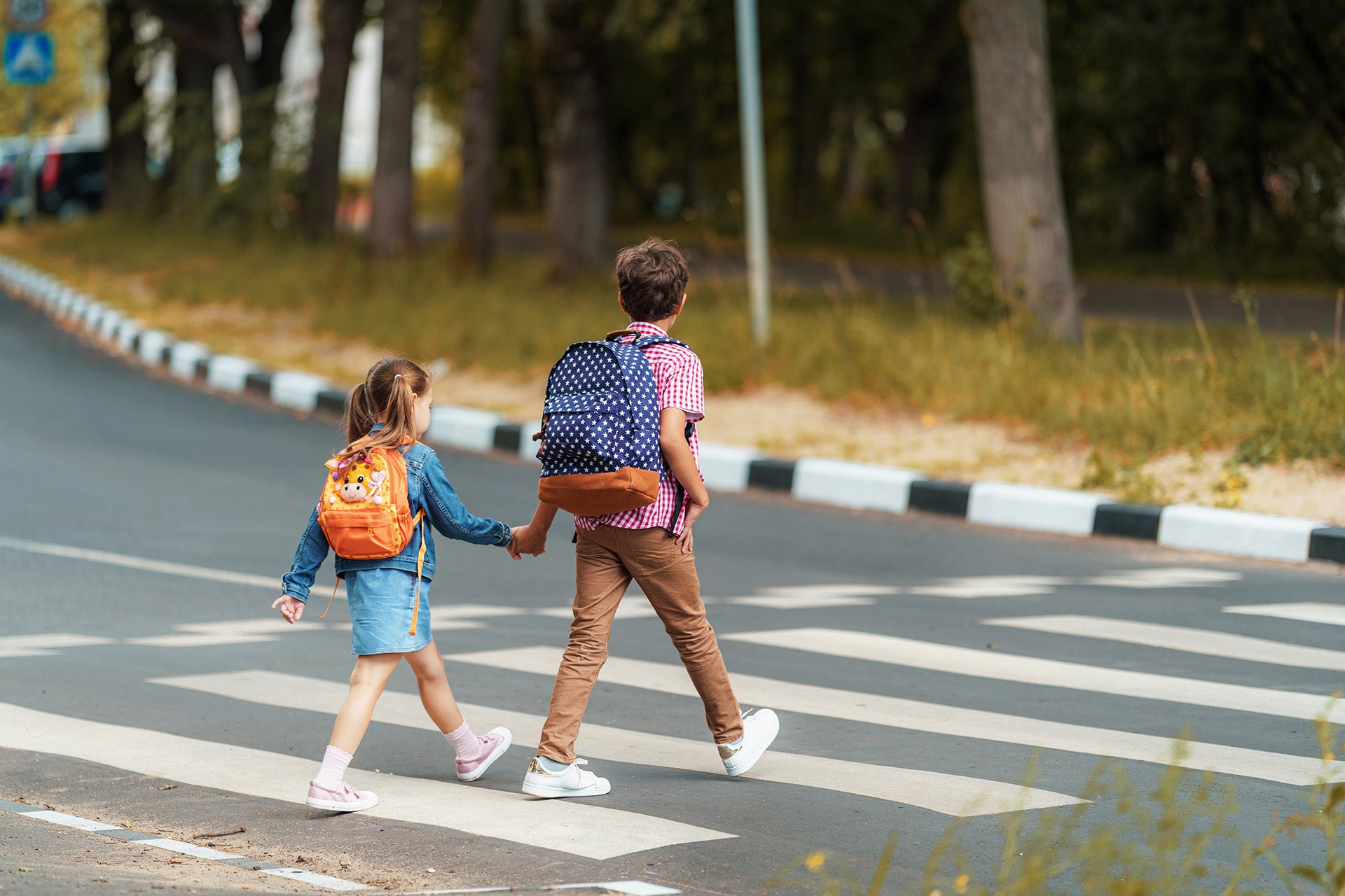 Two children walk across a marked crosswalk