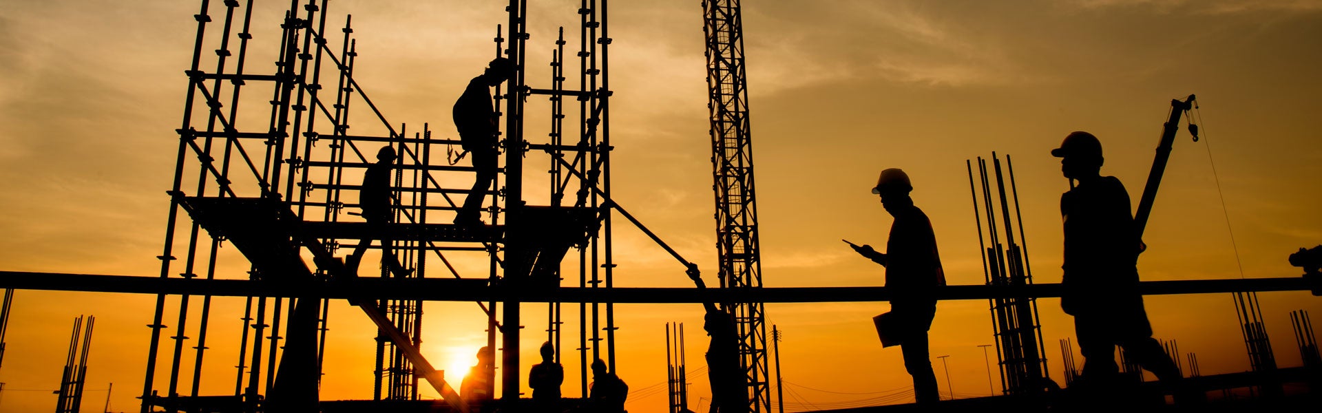 Construction workers on scaffolding at sunset